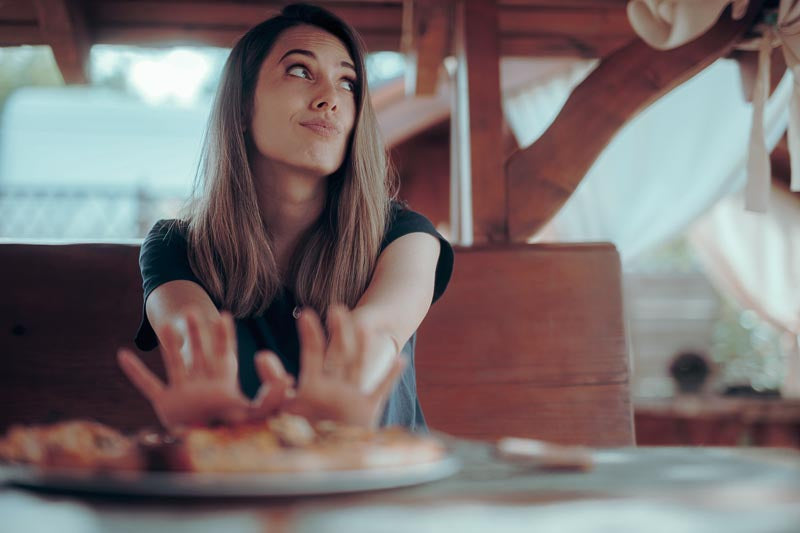 Frau schiebt das servierte Essen ablehnend zur Seite